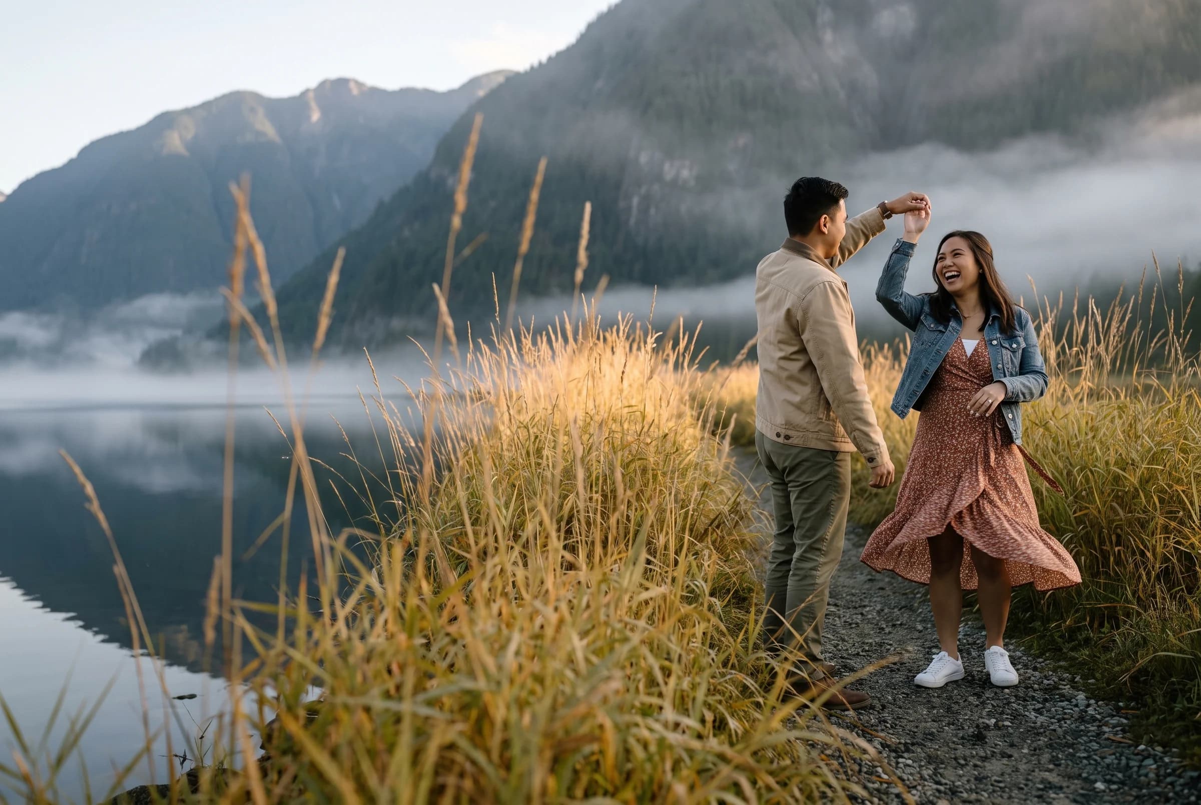 Couple dancing on a dyke path among tall golden reeds at Pitt Lake with mist on the water and mountains behind