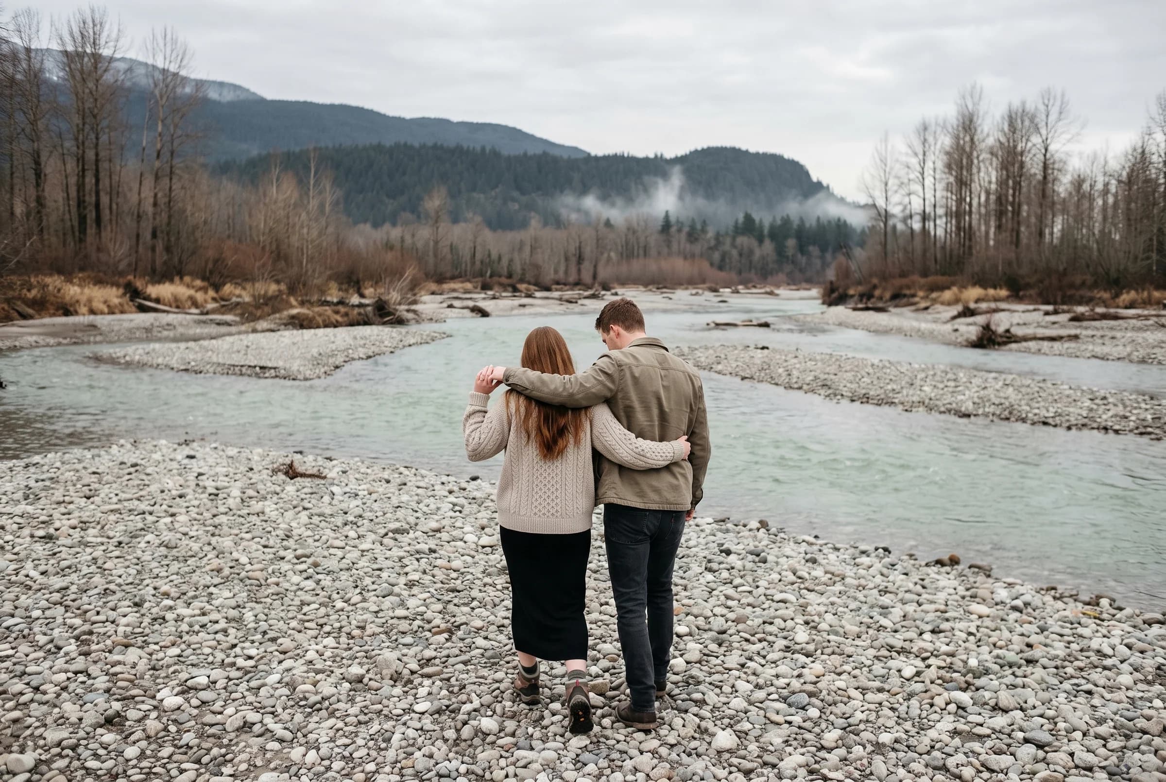 Couple seen from behind walking across the pale gravel bars of the Vedder River in Chilliwack
